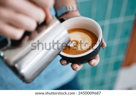 A person pouring milk into a cup of coffee
