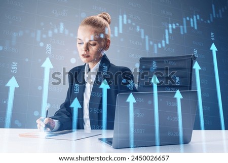 Attractive young woman at desk with laptop and growing blue vertical arrows and candlestick forex chart on blurry index grid background. Economic growth and increase concept. Double exposure