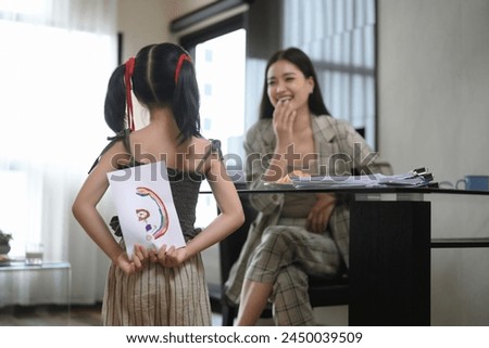 Cute little girl hiding greeting card for mother behind back