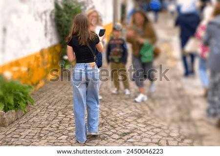 Back view of a young girl walking in the street with her friends in the background