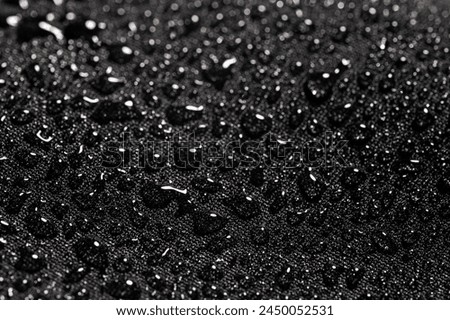 Close-up view on water drops on waterproof impregnated fabric in rain. Royalty-Free Stock Photo #2450052531