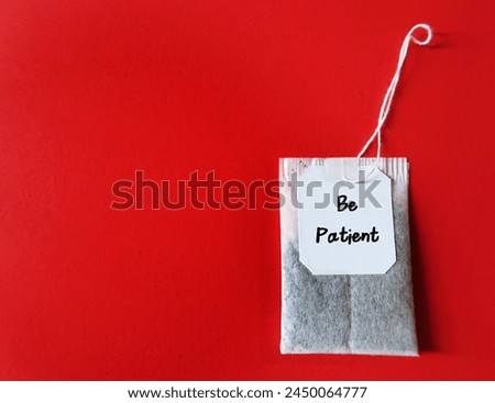 Tea back on copy space red background with text written Be Patient - positive message to remind oneself to have patience - keep calm and deal with frustrating situations calmly