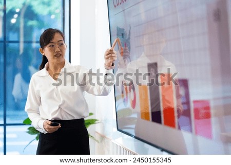 Presentation - Asian business woman people giving presentation and Report pointing at projector or TV screen. People Work in Business Office.