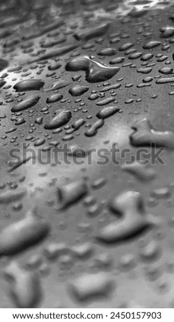 black and white photo, raindrops on a dark glass surface, background. Vertical photo, low key