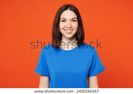 Young smiling happy cheerful satisfied woman she wear blue t-shirt casual clothes look camera with toothy smile isolated on plain red orange color wall background studio portrait. Lifestyle concept