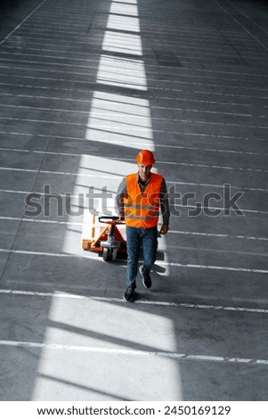Top view of engineer, factory worker wearing hard hat, vest, and work wear using forklift to deliver boxes for production, copy space. Transportation concept