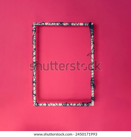 Creative picture frame concept with wool. Pink background with copy space. 