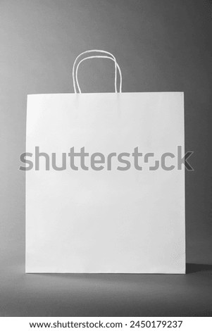 One white paper bag on grey background. Mockup for design