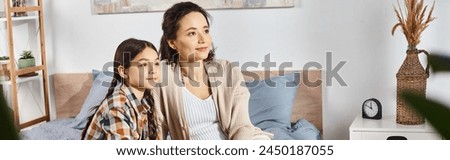 A woman sitting close to a young girl on a cozy bed, sharing heartfelt moments together at home. Royalty-Free Stock Photo #2450187055