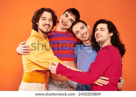 cheerful debonair gay men with makeup in vibrant attires posing actively together, pride month Royalty-Free Stock Photo #2450203809