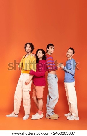 four debonair appealing cheerful gay men in vibrant clothes posing together actively, pride month Royalty-Free Stock Photo #2450203837
