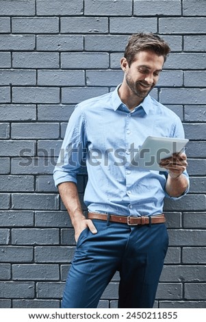 Business man, tablet and research, reading email or info online on a wall background in city. Smile, digital technology and professional on website, app or financial consultant networking on internet