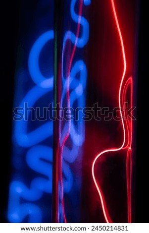 A purple and blue glowing tube with a red line running through it. The tube is lit up and he is a neon light