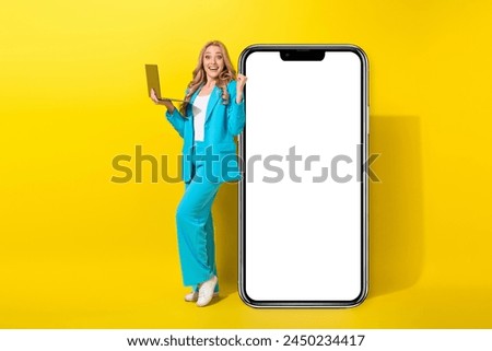 Full size photo of excited crazy girl dressed blue jacket hold laptop near smartphone display win lottery isolated on yellow background