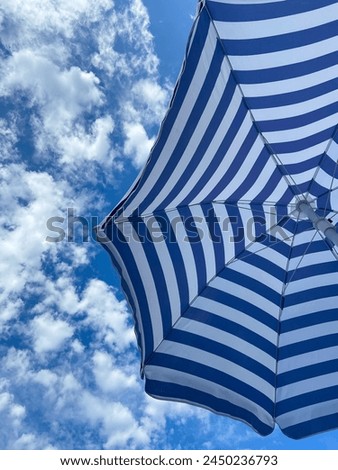 sun umbrella with white and blue stripes Royalty-Free Stock Photo #2450236793