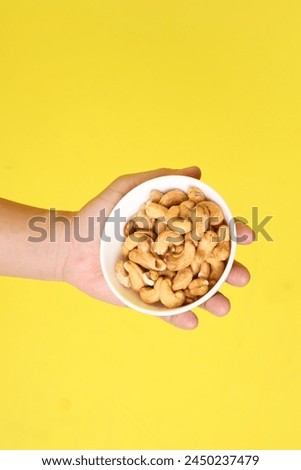 Hands holding almond isolate on yellow background. Chinese vegetarian festival Nine emperor god, J festival.
