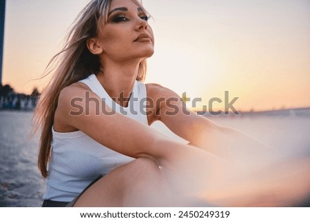 Serene woman in white enjoying a golden sunset, exuding a sense of calm and elegance against an evocative backdrop Royalty-Free Stock Photo #2450249319