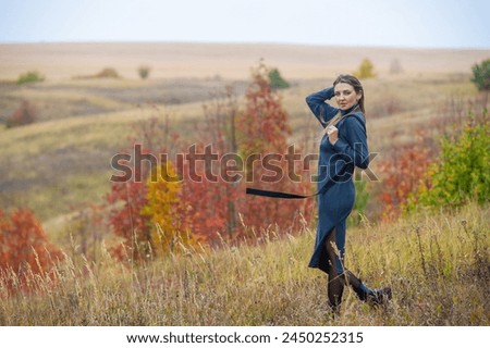 Autumn themed photo shoot with a girl in a warm gray dress. Beautiful colorful trees and hilly landscapes as a background. It visually captures the essence of the fall season in a stunning way.