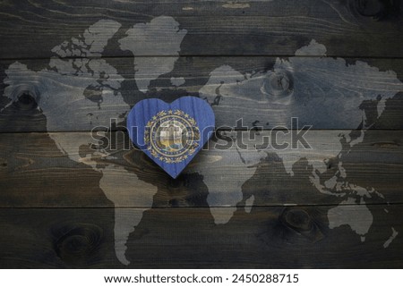 wooden heart with national flag of new hampshire state near world map on the wooden background. concept