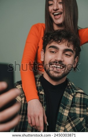 Vertical picture of a couple wearing casual wears looking at mobile screen while taking a picture isoalted over grey background.