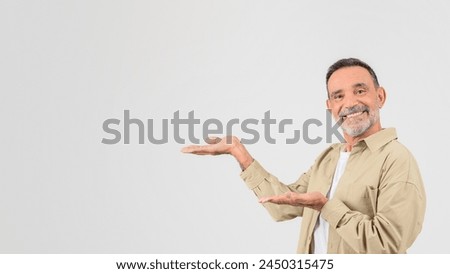Smiling old man presenting with an open hand gesture, isolated on a white background, panorama with copy space Royalty-Free Stock Photo #2450315475