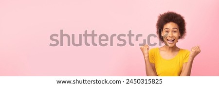 Joyful african american woman celebrating with hands raised in triumph against a minimalist pink background, perfect for mockup or web-banner