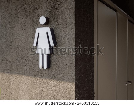 Urinary Urgency Toilet Sign for women at the entrance to a public toilet. Comic toilet sign symbols with woman on black brick background. Copy space.