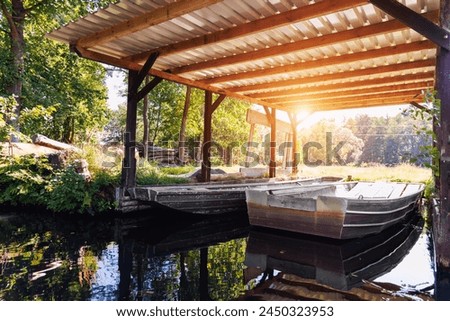Old metal boat moored under shed shelter wooden canopy rustic boathouse at countryside in Spreewald canal national biosphere reserve house. Scenic Vintage water transport warm morning sunrise Royalty-Free Stock Photo #2450323953