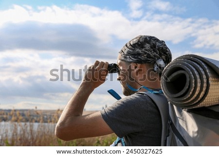 Young man looking at the horizon with binoculars outdoor. man using binoculars in sunset nature