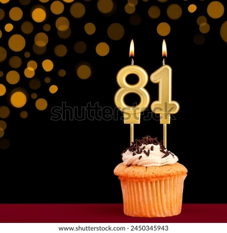 Number 81 birthday candle - Cupcake on black background with out of focus lights