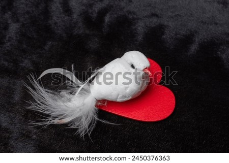 Fake bird holding little heart icon on dark color background
