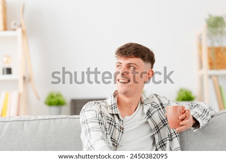 Young man relaxed at home with a cup of coffee sitting on the sofa