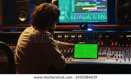 Audio technician working with music recording software and editing tunes, mixing console and control panel board in post production studio. Producer operating technical equipment. Camera A.