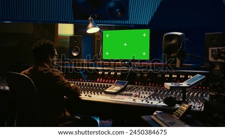 African american sound engineer working in control room with mixing console, tracking music and editing by adjusting volume levels. Skilled technician adjusting volume levels with buttons. Camera B.
