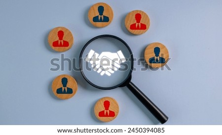 A magnifying glass is used to look at a group of people. The people are wearing ties and are holding hands. Concept of unity and collaboration