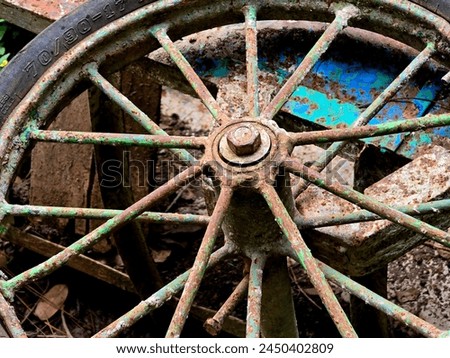 Time-worn and weathered, this vintage wheel's rusted spokes tell stories of bygone travels and enduring resilience. Royalty-Free Stock Photo #2450402809