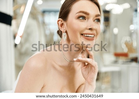 A young, beautiful brunette bride poses elegantly in a white dress in a wedding salon, exuding grace and poise.