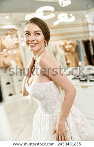 A beautiful, young brunette bride in a white dress striking a serene pose in a wedding salon.