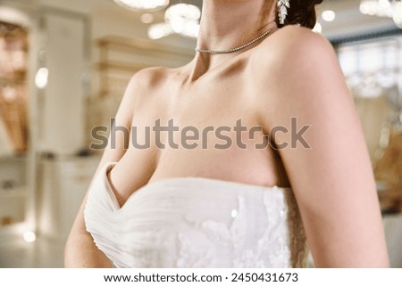 A young brunette bride in a white dress strikes a pose in a wedding salon, radiating elegance and beauty.