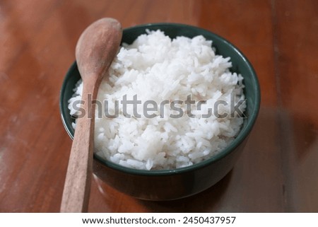 One bowl of white rice and wooden spoon on brown wooden table, food, stock photo.