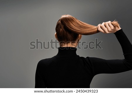 Back view of young stylish woman with long hair elegantly styled in a ponytail, exuding grace and confidence.