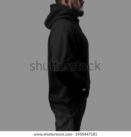 Template of a black oversized hoodie on a man in jeans, side, hood, label on the cuff, clothes isolated on background. Mockup of male clothing on a guy with hands in pocket, sweatshirt for design
