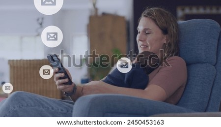 Image of social media icons over caucasian woman holding baby and using smartphone. Social media, communication and digital interface concept digitally generated image.