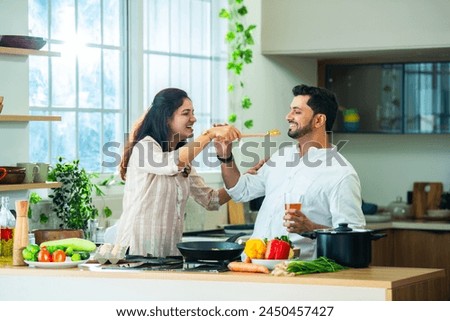 Happy loving Indian asian young couple cooking food in kitchen together, hugging, standing at table
