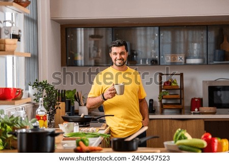 Indian young handsome man in kitchen taking selfie picture while cooking, 