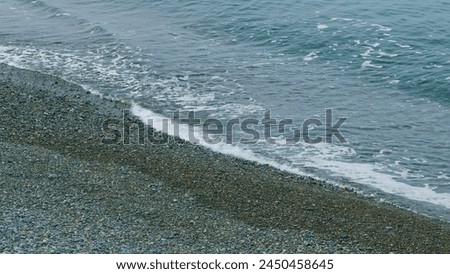 Soft Waves, With White Foam Are Washed Ashore. Wave Is Incident On The Beach Of Pebbles. Still. Royalty-Free Stock Photo #2450458645
