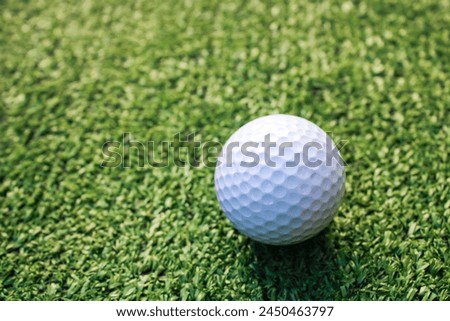 A picture of a white golf ball placed on artificial grass in the center of the picture.