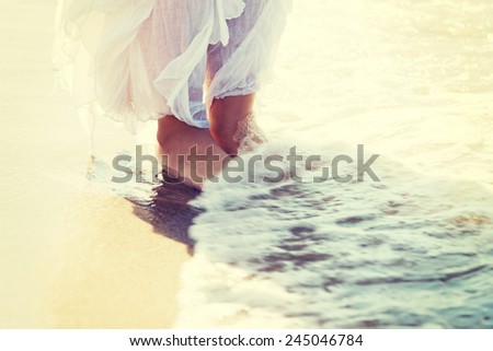 Picture of feet on a beach and water. Over splashing water.