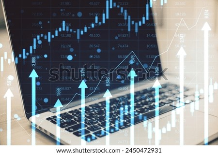 Close up of laptop at desk with growing blue vertical arrows and candlestick forex chart on blurry index grid background. Economic growth and increase concept. Double exposure