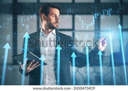 Attractive european businessman with tablet using growing blue vertical arrows and candlestick forex chart on blurry office index background. Economic growth and increase concept. Double exposure